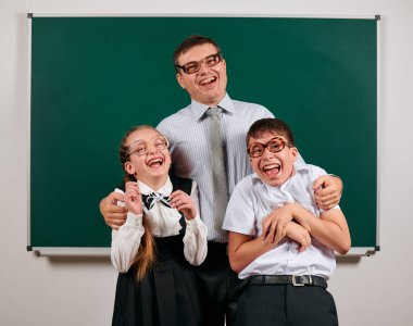 Bir öğretmen, okul çocuğu ve eski moda gözlük ile okul öncesi portre kara tahta arka plan üzerinde poz - geri okul ve eğitim kavramı