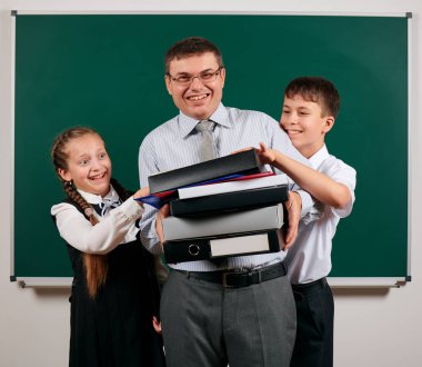 Klasörler, belgeler ve evrak çantası ile iş elbisesi giymiş bir öğretmenin portresi, kara tahta arka plan da okul çocuğu ve kız öğrenci ile poz - öğrenme ve eğitim kavramı