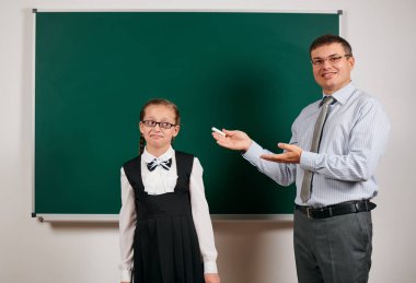 Portrait of a teacher and schoolgirl like as excellent pupil, posing at blackboard background - back to school and education concept clipart