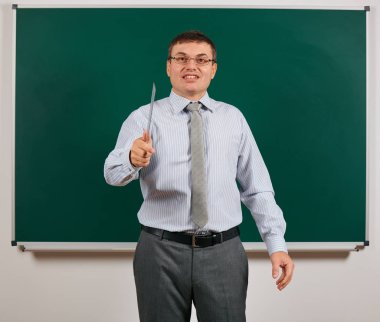 İş elbisesi içinde okul öğretmeni kılığında, tahta arka planda poz veren duygusal konuşan bir adamın portresi - öğrenme ve eğitim konsepti