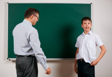 Düşük disiplinli bir öğretmen ve komik bir öğrencinin portresi, kötü okul performansı, kara tahta arka planda poz - geri okul ve eğitim kavramı