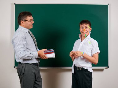 Düşük disiplinli bir öğretmen ve komik bir öğrencinin portresi, kötü okul performansı, kara tahta arka planda poz - geri okul ve eğitim kavramı