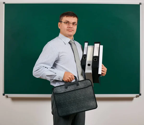 Retrato de um homem vestido em terno de negócios com pastas, documentos e pasta, posando em fundo de quadro-negro - conceito de aprendizagem e educação — Fotografia de Stock