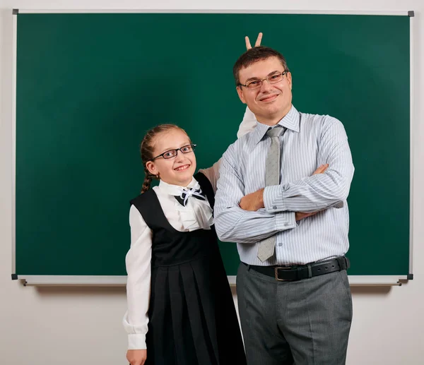 Portrait of a teacher and schoolgirl, posing at blackboard background - back to school and education concept — Stock Photo, Image