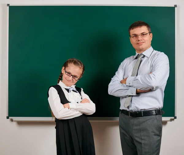 Portret van een leraar en schoolmeisje, poseren op Blackboard achtergrond-terug naar school en onderwijsconcept — Stockfoto