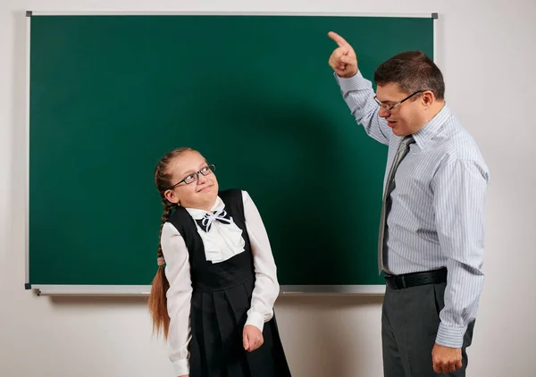 Angry teacher shout to schoolgirl, posing at blackboard background - back to school and education concept — Stock Photo, Image