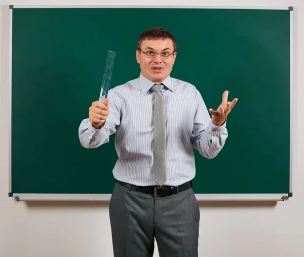 Retrato de um homem falante emocional vestido como um professor de escola em terno de negócios, posando em fundo de quadro-negro - conceito de aprendizagem e educação — Fotografia de Stock