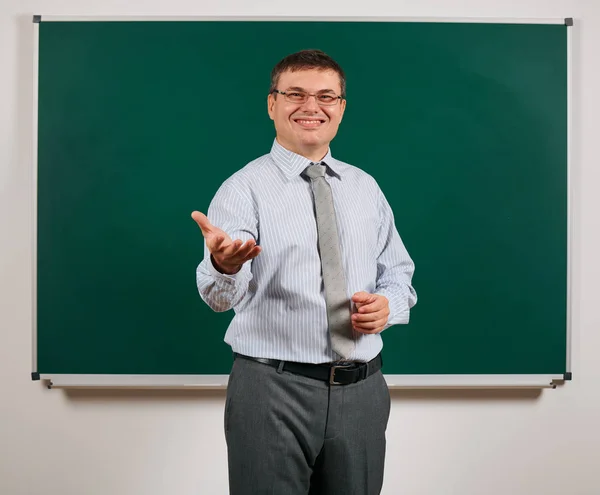 Retrato de un hombre vestido como un maestro de escuela en traje de negocios, posando en el fondo de pizarra aprendizaje y concepto de educación —  Fotos de Stock