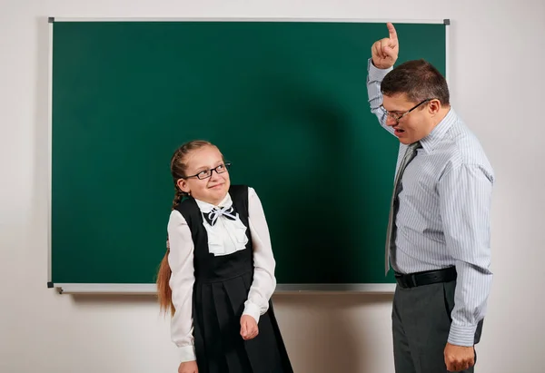 Enseignante en colère crier à l'écolière, posant sur fond de tableau noir - concept de retour à l'école et de l'éducation — Photo