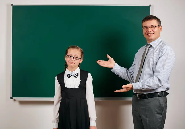 Portret van een leraar en schoolmeisje als een uitstekende leerling, poseren op Blackboard achtergrond-terug naar school en onderwijsconcept — Stockfoto