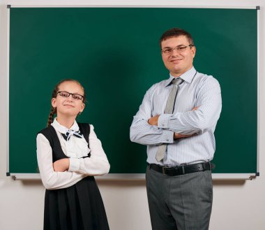 Bir öğretmen ve kız öğrenci portresi, kara tahta arka planda poz - geri okul ve eğitim kavramı