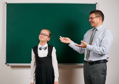 Mükemmel bir öğrenci gibi bir öğretmen ve kız öğrenci portresi, kara tahta arka planda poz - geri okul ve eğitim kavramı