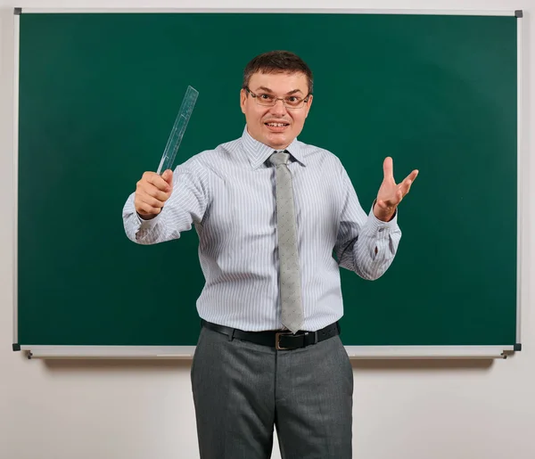 Portret van een emotionele pratende man gekleed als een school leraar in Business Suit, poseren op Blackboard background-learning en Education concept — Stockfoto