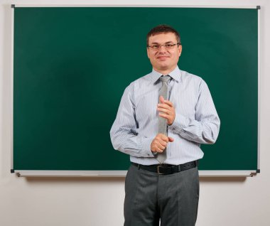 İş elbisesi içinde okul öğretmeni kılığına girmiş, tahta arka planda poz veren bir adamın portresi - öğrenme ve eğitim konsepti