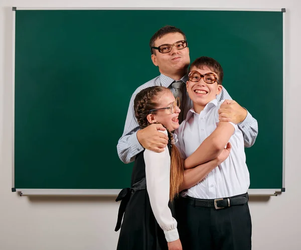 Retrato de un maestro, colegial y colegiala con anteojos anticuados posando sobre un fondo de pizarra: vuelta a la escuela y concepto de educación — Foto de Stock
