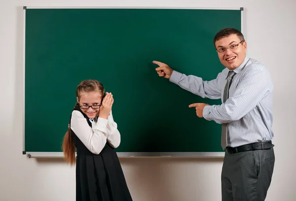 Boze leraar schreeuwen naar schoolmeisje, poseren op Blackboard achtergrond-terug naar school en onderwijsconcept — Stockfoto