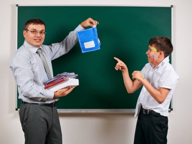 Düşük disiplinli bir öğretmen ve komik bir öğrencinin portresi. Öğrenci çok duygusal, eğlenceli ve çok mutlu, kara tahta arka planda poz - geri okul ve eğitim kavramı