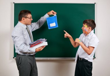 Düşük disiplinli bir öğretmen ve komik bir öğrencinin portresi. Öğrenci çok duygusal, eğlenceli ve çok mutlu, kara tahta arka planda poz - geri okul ve eğitim kavramı