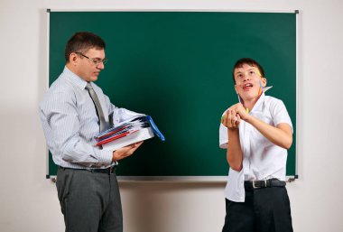 Düşük disiplinli bir öğretmen ve komik bir öğrencinin portresi. Öğrenci çok duygusal, eğlenceli ve çok mutlu, kara tahta arka planda poz - geri okul ve eğitim kavramı