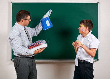 Düşük disiplinli bir öğretmen ve komik bir öğrencinin portresi. Öğrenci çok duygusal, eğlenceli ve çok mutlu, kara tahta arka planda poz - geri okul ve eğitim kavramı