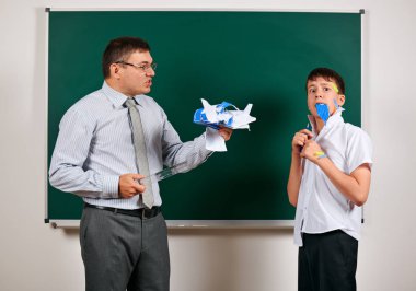 Düşük disiplinli bir öğretmen ve komik bir öğrencinin portresi. Öğrenci çok duygusal, eğlenceli ve çok mutlu, kara tahta arka planda poz - geri okul ve eğitim kavramı