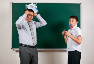 Düşük disiplinli bir öğretmen ve komik bir öğrencinin portresi. Öğrenci çok duygusal, eğlenceli ve çok mutlu, kara tahta arka planda poz - geri okul ve eğitim kavramı