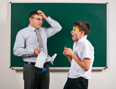 Düşük disiplinli bir öğretmen ve komik bir öğrencinin portresi. Öğrenci çok duygusal, eğlenceli ve çok mutlu, kara tahta arka planda poz - geri okul ve eğitim kavramı