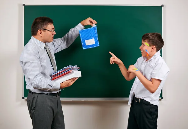 Portrait of a teacher and funny schoolboy with low discipline. Pupil very emotional, having fun and very happy, posing at blackboard background - back to school and education concept — Stock Photo, Image