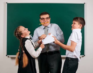 Bir öğretmenin ev ödevi kontrol portresi, okul egzersiz kitapları okuma, eski moda gözlük ile okul çocuğu ve kız öğrenci kara tahta arka plan üzerinde poz - geri okul ve eğitim kavramı