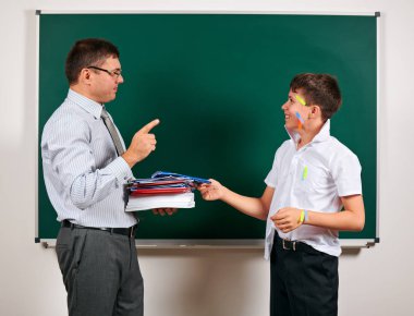 Düşük disiplinli bir öğretmen ve komik bir öğrencinin portresi. Öğrenci çok duygusal, eğlenceli ve çok mutlu, kara tahta arka planda poz - geri okul ve eğitim kavramı