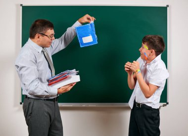 Düşük disiplinli bir öğretmen ve komik bir öğrencinin portresi. Öğrenci çok duygusal, eğlenceli ve çok mutlu, kara tahta arka planda poz - geri okul ve eğitim kavramı