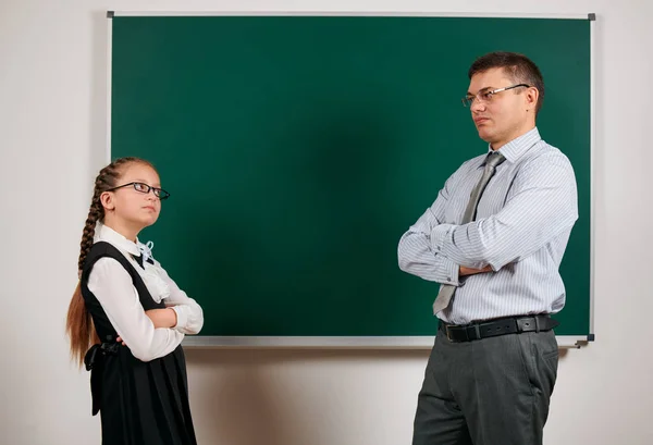 Portrait of a teacher and schoolgirl, posing at blackboard background - back to school and education concept — Stock Photo, Image