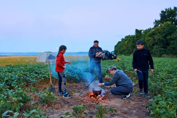 Famiglia in viaggio e in campeggio, crepuscolo, cucina sul fuoco. Bella natura - campo, foresta e luna . — Foto Stock