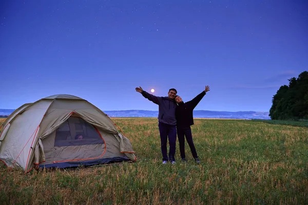 Familia viajando y acampando, crepúsculo, posando cerca de la tienda. Hermosa naturaleza - campo, bosque, estrellas y luna. Padre, hijo y niña sentados en la tienda . —  Fotos de Stock