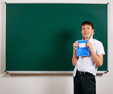 Komik öğrenci portresi. Okul çocuk çok duygusal, eğlenceli ve çok mutlu, kara tahta arka plan sahip - geri okul ve eğitim kavramı
