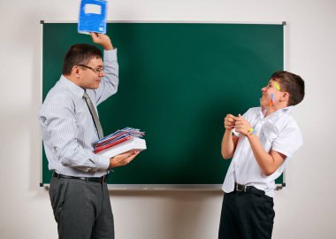 Düşük disiplinli bir öğretmen ve komik bir öğrencinin portresi. Öğrenci çok duygusal, eğlenceli ve çok mutlu, kara tahta arka planda poz - geri okul ve eğitim kavramı