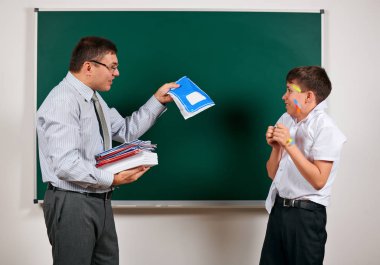 Düşük disiplinli bir öğretmen ve komik bir öğrencinin portresi. Öğrenci çok duygusal, eğlenceli ve çok mutlu, kara tahta arka planda poz - geri okul ve eğitim kavramı