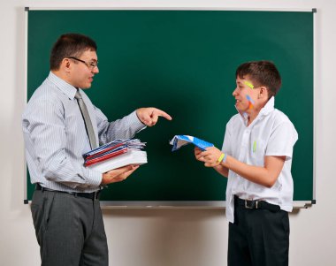 Düşük disiplinli bir öğretmen ve komik bir öğrencinin portresi. Öğrenci çok duygusal, eğlenceli ve çok mutlu, kara tahta arka planda poz - geri okul ve eğitim kavramı