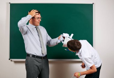 Düşük disiplinli bir öğretmen ve komik bir öğrencinin portresi. Öğrenci çok duygusal, eğlenceli ve çok mutlu, kara tahta arka planda poz - geri okul ve eğitim kavramı