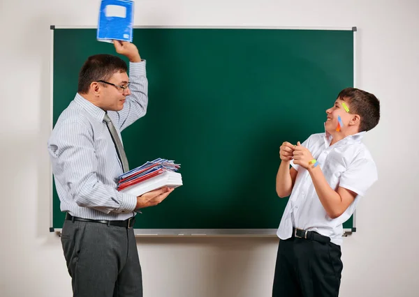 Portret van een leraar en grappige school jongen met lage discipline. Leerling zeer emotioneel, plezier en zeer gelukkig, poseren op Blackboard achtergrond-terug naar school en onderwijsconcept — Stockfoto