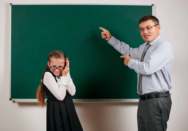 Angry teacher shout to schoolgirl, posing at blackboard background - back to school and education concept — Stock Photo, Image