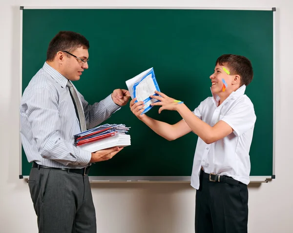 Portrait of a teacher and funny schoolboy with low discipline. Pupil very emotional, having fun and very happy, posing at blackboard background - back to school and education concept — Stock Photo, Image