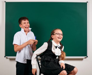 Bir okul çocuğu ve kız öğrenci nin kara tahta arka plan yakınında oynayan portresi - geri okul ve eğitim kavramı
