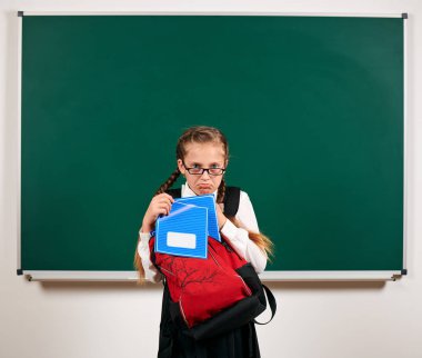 Sırt çantası ve kara tahta arka plan yakın okul malzemeleri ile bir kız öğrenci portresi - geri okul ve eğitim kavramı