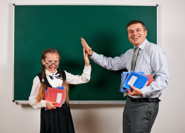 Bir öğretmen ve kız öğrenci portresi, kara tahta arka planda poz - geri okul ve eğitim kavramı