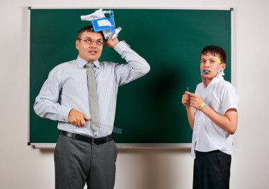 Düşük disiplinli bir öğretmen ve komik bir öğrencinin portresi. Öğrenci çok duygusal, eğlenceli ve çok mutlu, kara tahta arka planda poz - geri okul ve eğitim kavramı