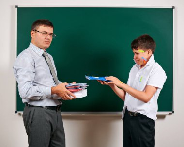 Düşük disiplinli bir öğretmen ve komik bir öğrencinin portresi. Öğrenci çok duygusal, eğlenceli ve çok mutlu, kara tahta arka planda poz - geri okul ve eğitim kavramı