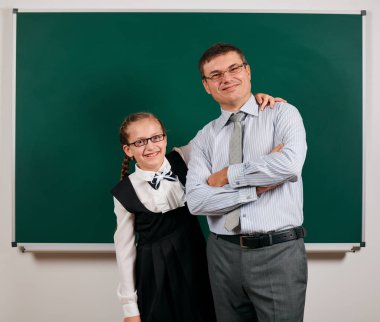 Bir öğretmen ve kız öğrenci portresi, kara tahta arka planda poz - geri okul ve eğitim kavramı