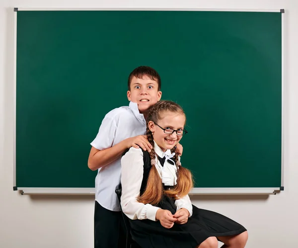 Portrait d'un écolier et d'une écolière jouant près du tableau noir - concept de retour à l'école et d'éducation — Photo