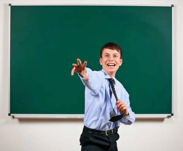 Retrato de un niño vestido de traje jugando cerca de la pizarra de fondo - volver a la escuela y el concepto de educación — Foto de Stock